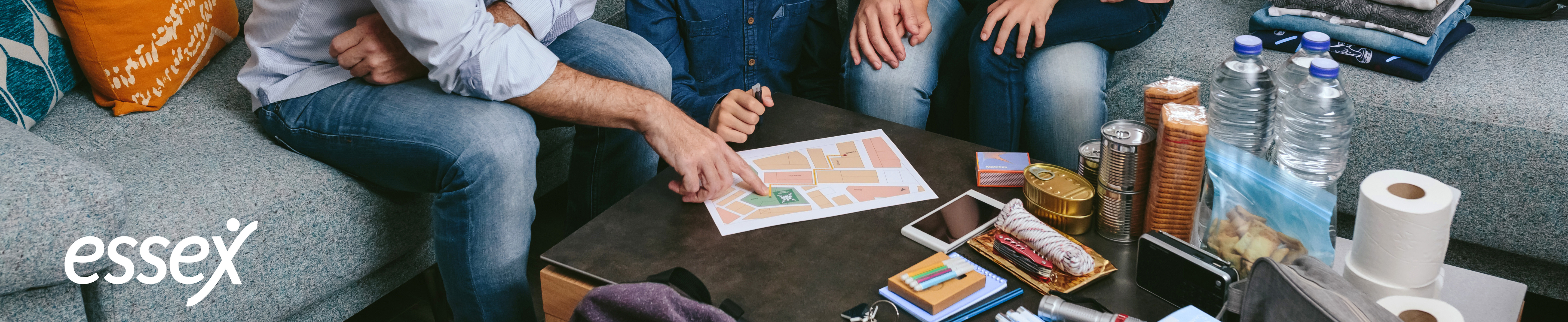 Family gathered around coffee table making an emergency 72hr kit. Essex logo.