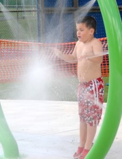 Water sprays boy at splashpad