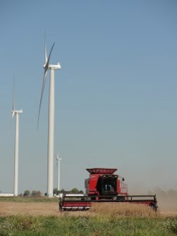 A combine cuts wheat below three turbines
