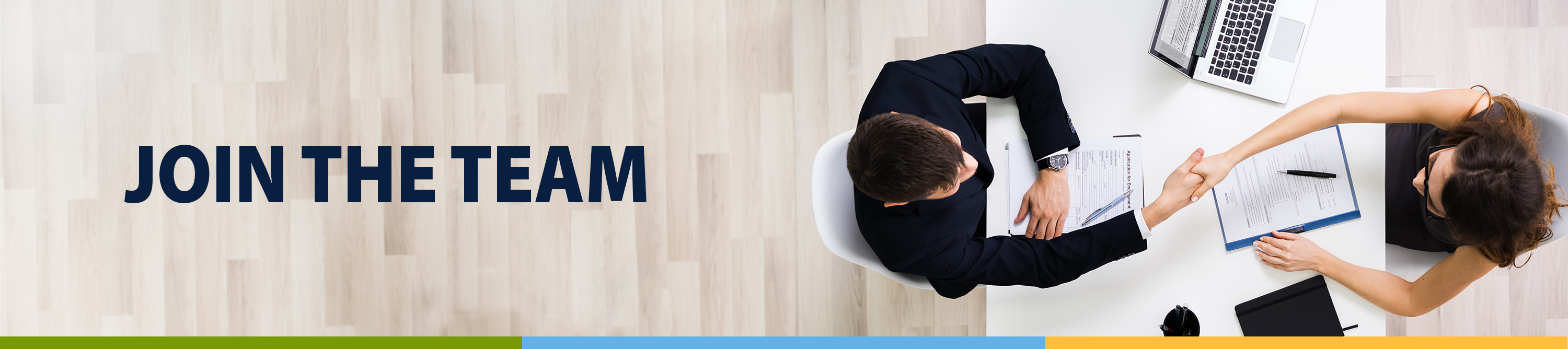 Join the Team. Photo of a man and women sitting across from each other at des, shaking hands.