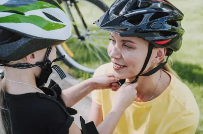 Daughter putting on mothers bike helmet